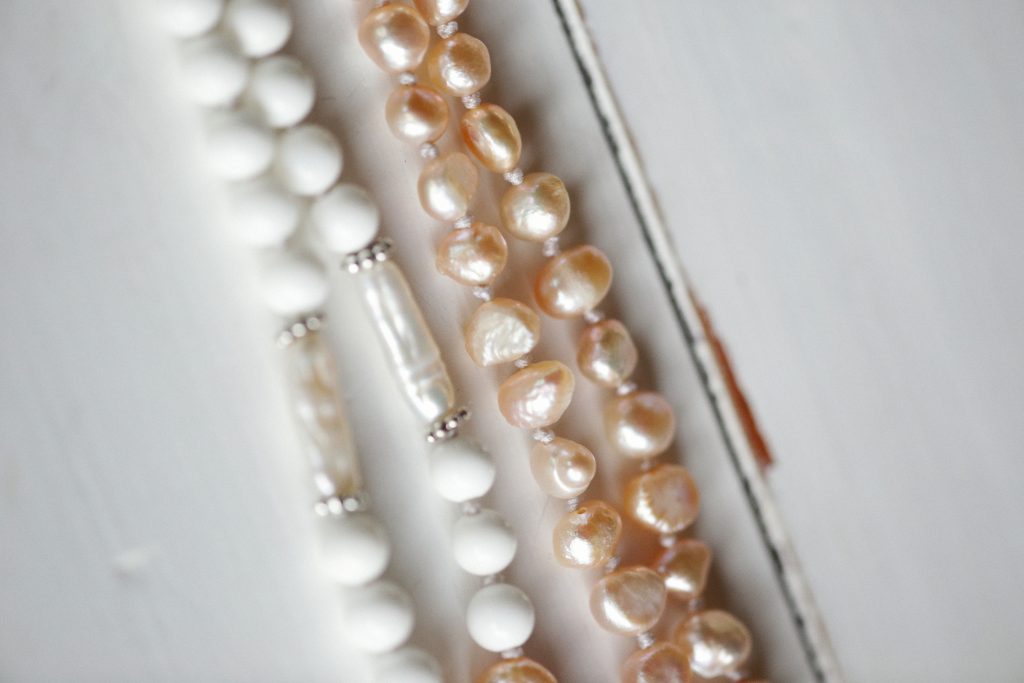 Close-up of elegant pearl and bead necklaces displayed on a white surface, showcasing delicate jewelry design.